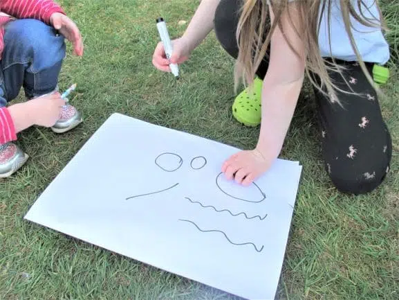 Preschoolers making pre-writing marks on large paper