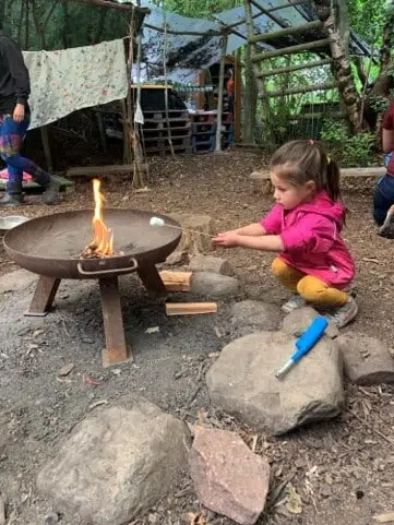 A child heating a marshmallow over a forest school fire