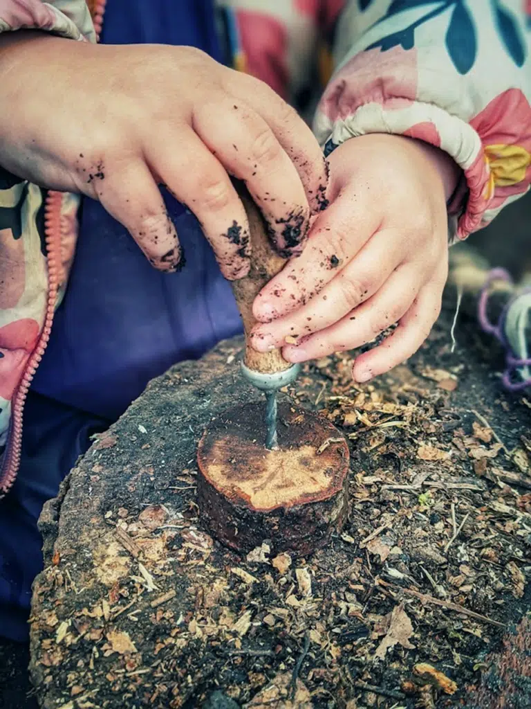 Handheld drill cutting a log slice