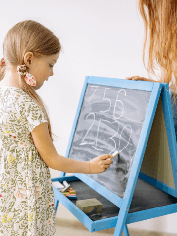 young girl writing on a black board