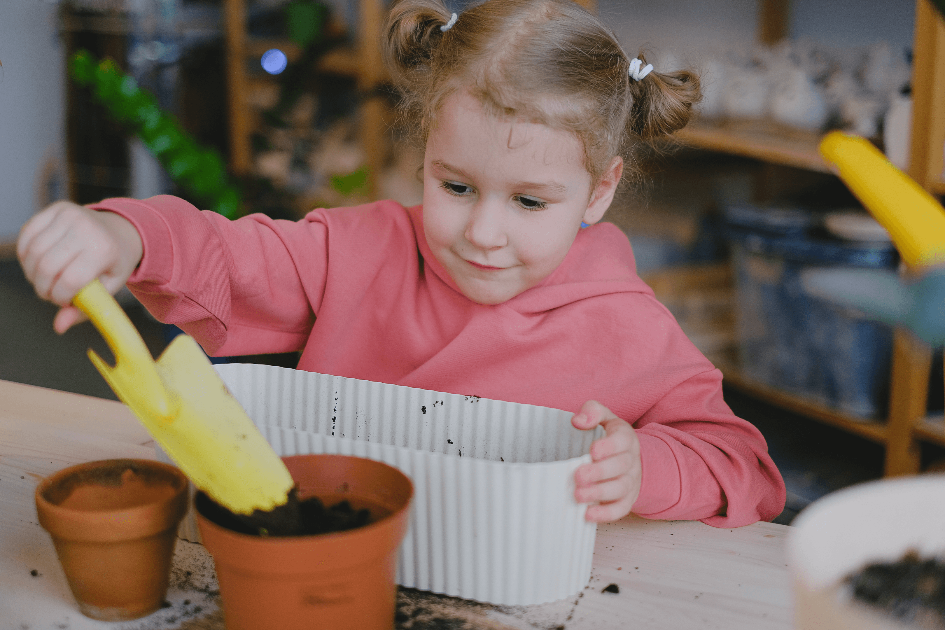 a girl putting soil in a pot using a garden trowel