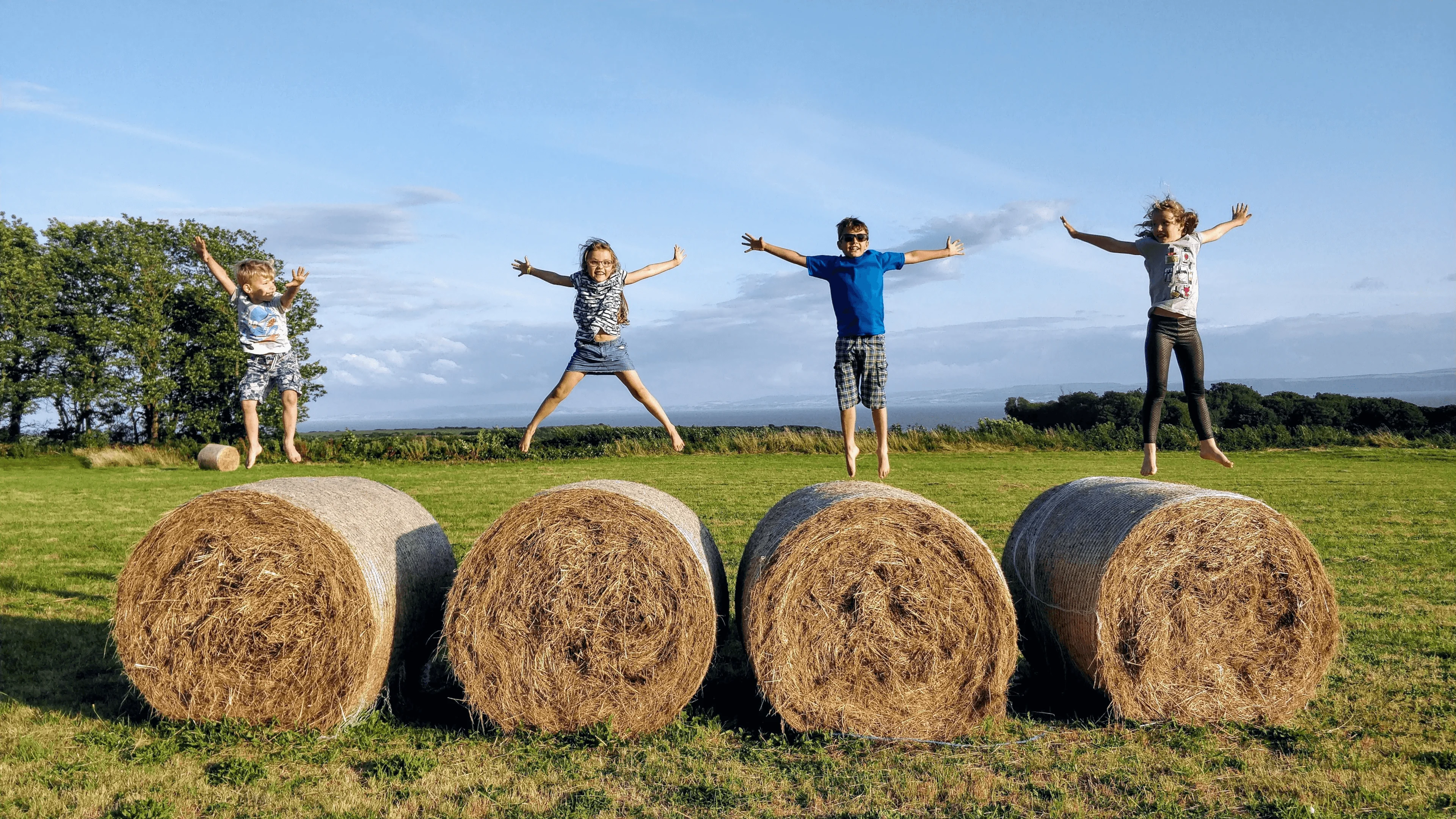 children jumping on brown hays during daytime