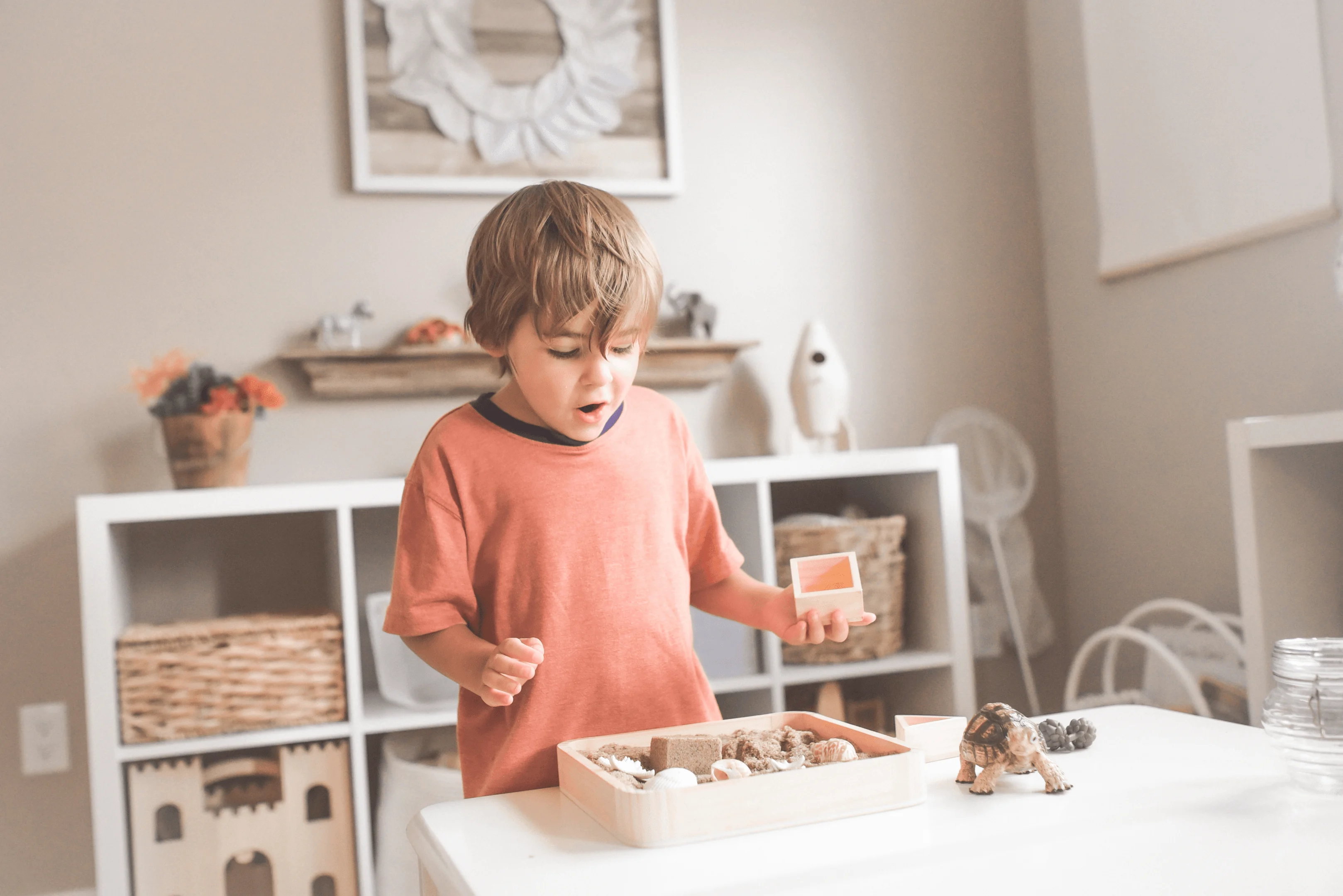 boy in orange crew neck t-shirt standing in front of white wooden table