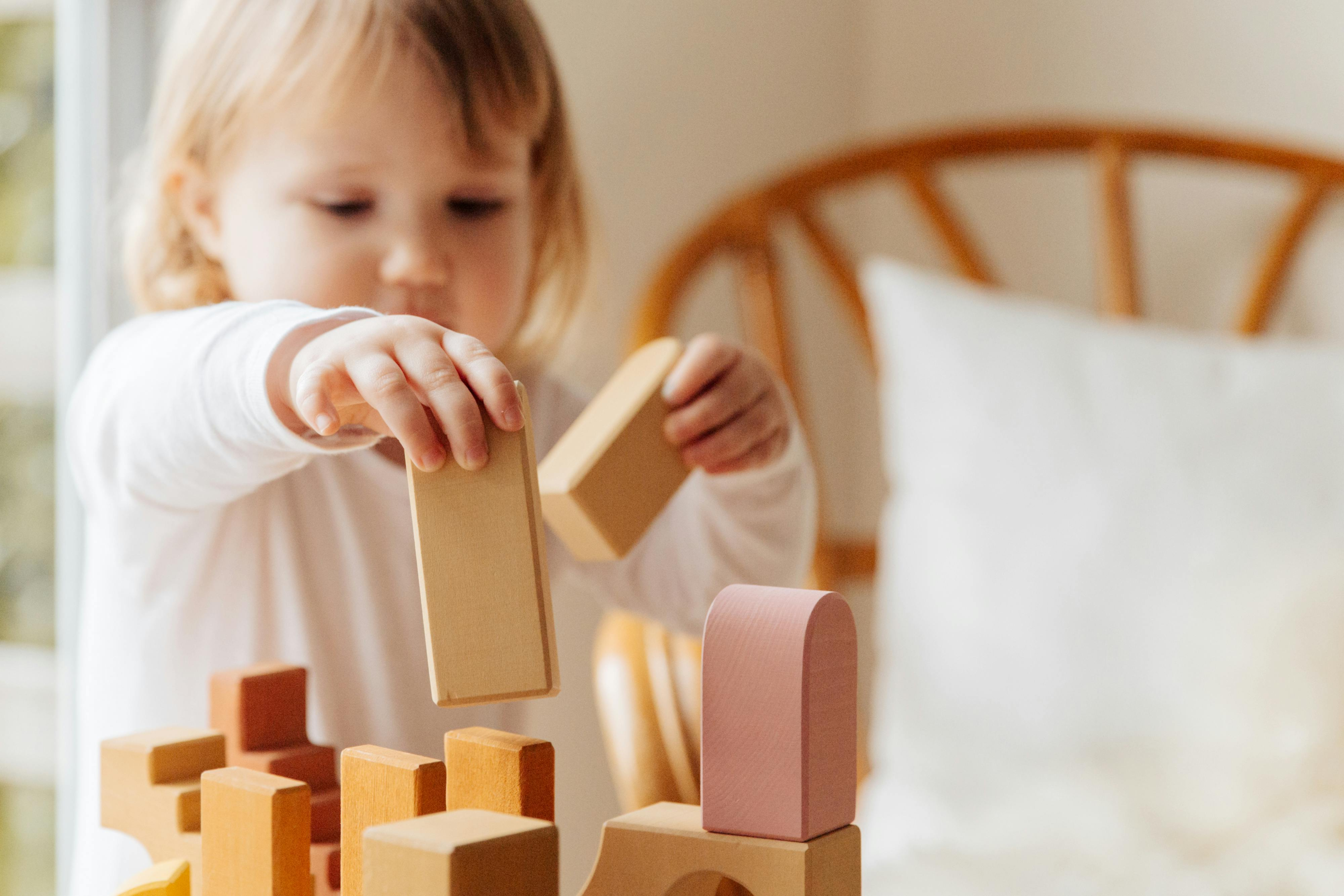 young girl playing with wooden block toys