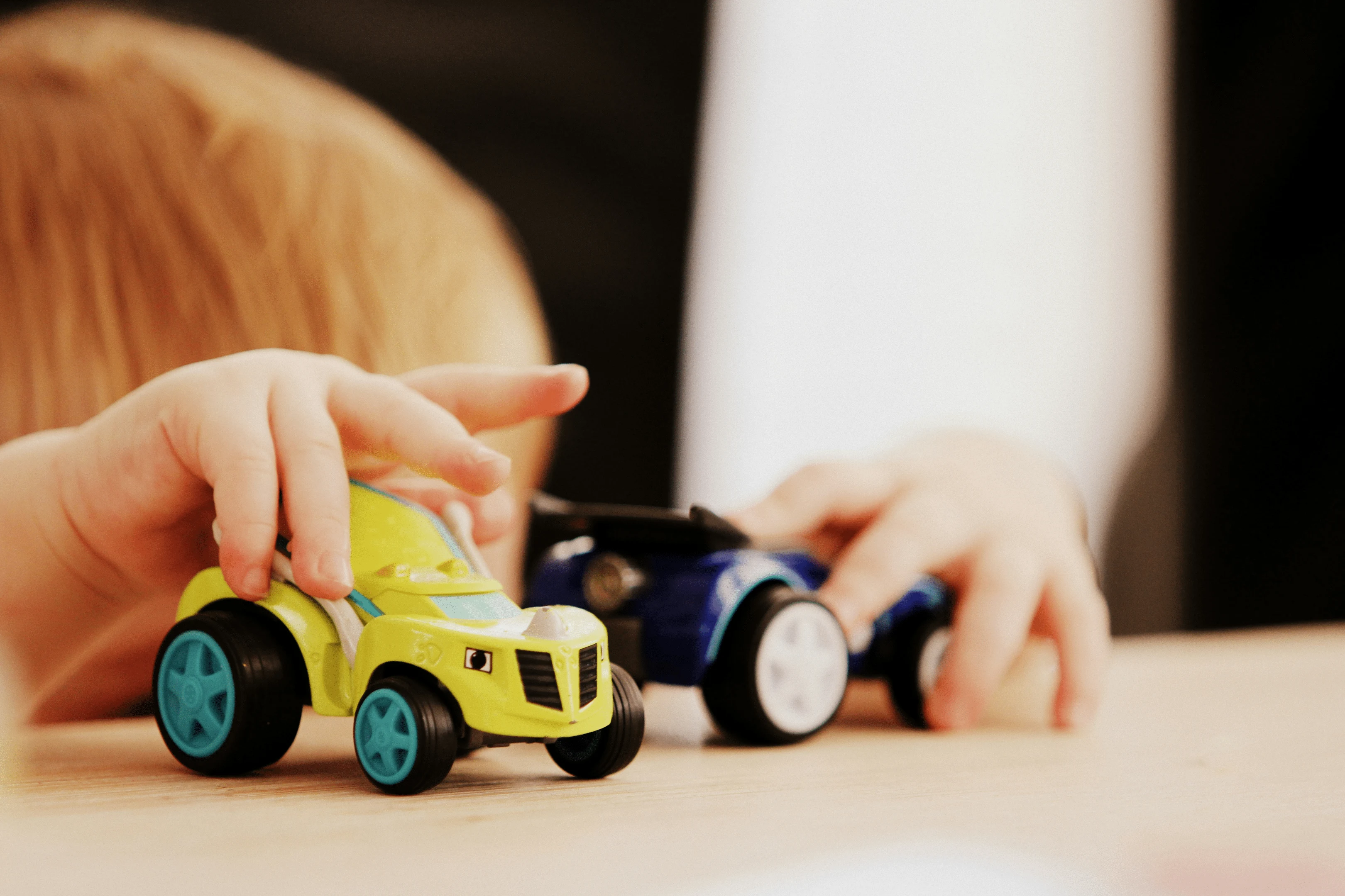 boy holding two toy cars 